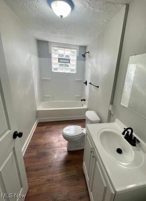 full bathroom with shower / tub combination, vanity, wood-type flooring, a textured ceiling, and toilet