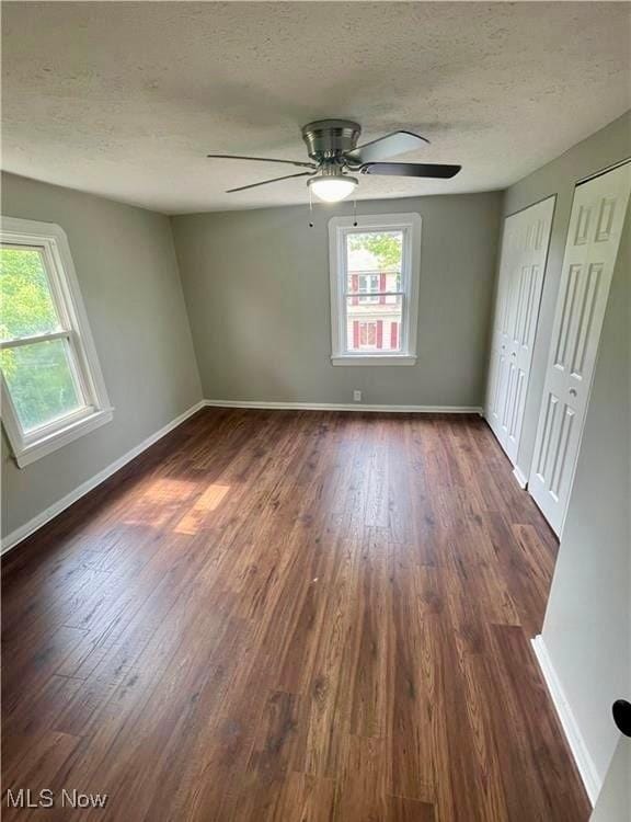 empty room with ceiling fan, a textured ceiling, and dark hardwood / wood-style flooring