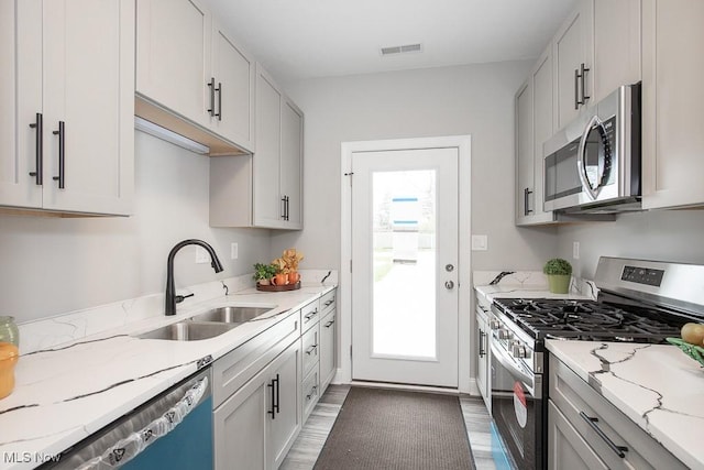 kitchen featuring light stone counters, sink, stainless steel appliances, and white cabinets