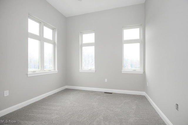 carpeted spare room featuring plenty of natural light