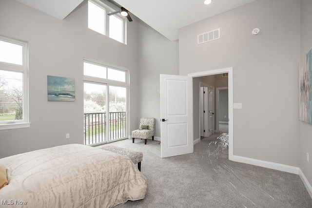 carpeted bedroom with access to exterior and a high ceiling