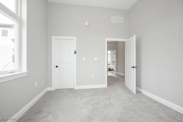 unfurnished bedroom with light colored carpet and a high ceiling