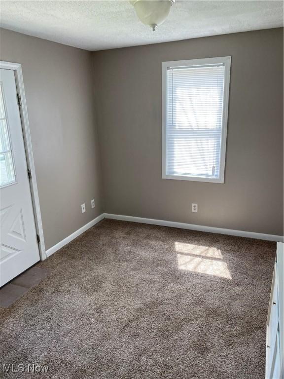 carpeted spare room featuring a textured ceiling