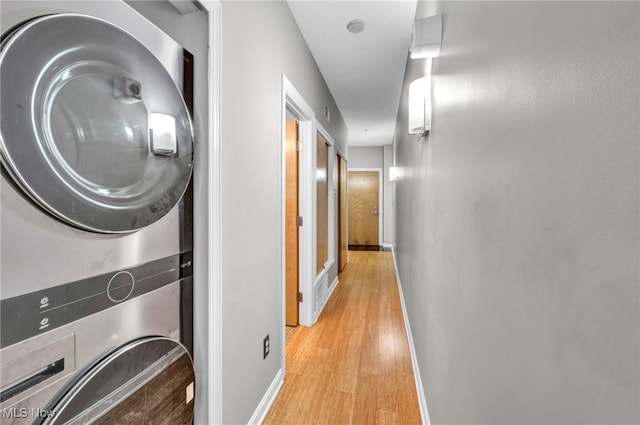 washroom featuring stacked washer and dryer and light hardwood / wood-style flooring