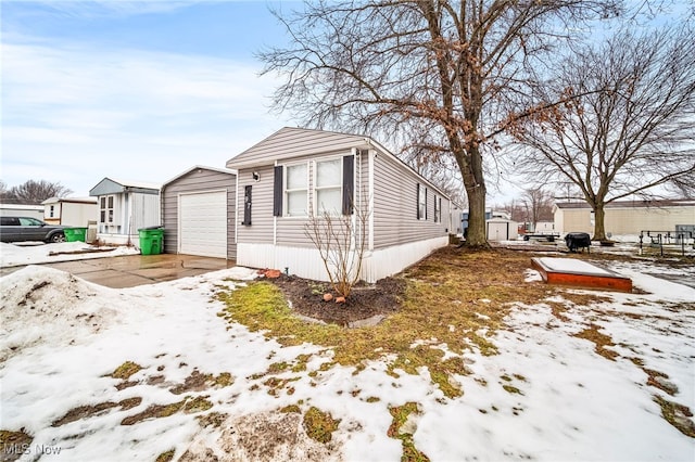 snow covered property with an outbuilding and a garage