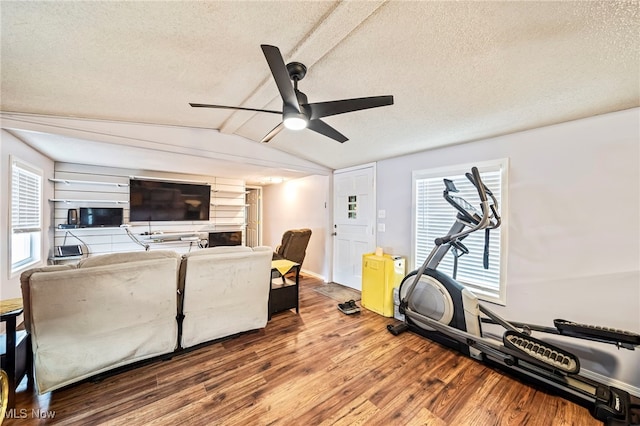 workout room with hardwood / wood-style flooring, vaulted ceiling, ceiling fan, and a textured ceiling