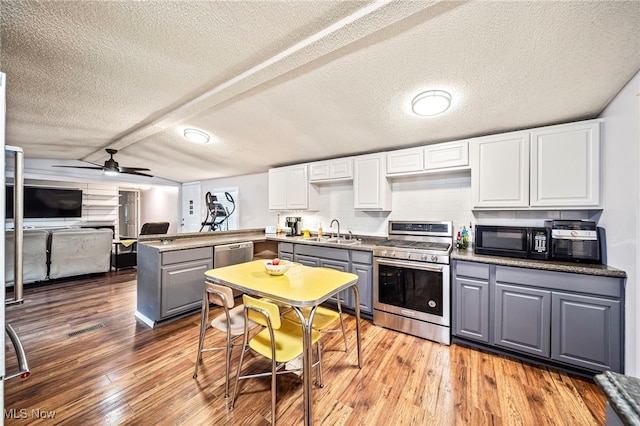 kitchen with sink, white cabinetry, kitchen peninsula, stainless steel appliances, and light hardwood / wood-style floors