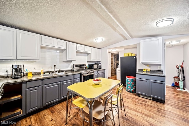 kitchen with sink, gray cabinetry, white cabinetry, stainless steel gas stove, and black refrigerator