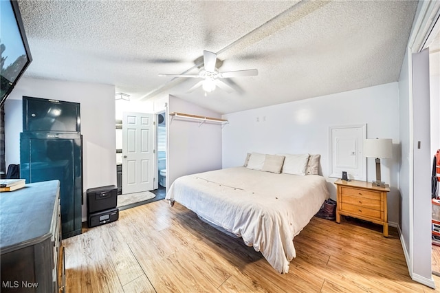 bedroom with a textured ceiling, vaulted ceiling, light hardwood / wood-style floors, and ceiling fan