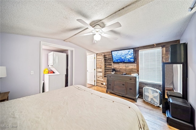 bedroom featuring vaulted ceiling, washer / dryer, a textured ceiling, and light hardwood / wood-style floors