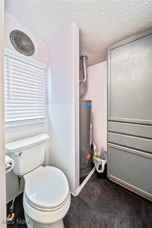 bathroom featuring gas water heater, a textured ceiling, and toilet