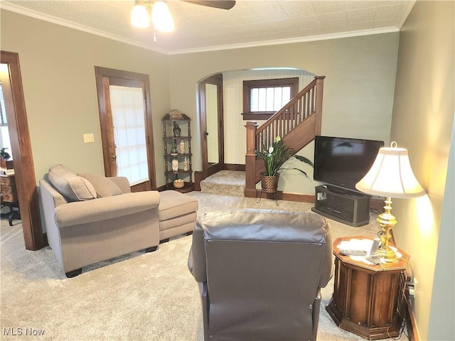 living room with ceiling fan, ornamental molding, and light carpet