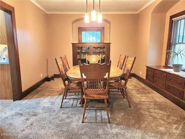 carpeted dining space with crown molding