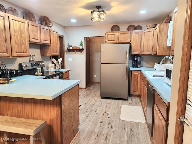 kitchen with appliances with stainless steel finishes, a breakfast bar, light hardwood / wood-style floors, and kitchen peninsula