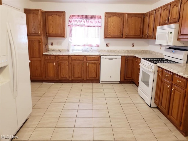 kitchen with light stone counters, sink, and white appliances