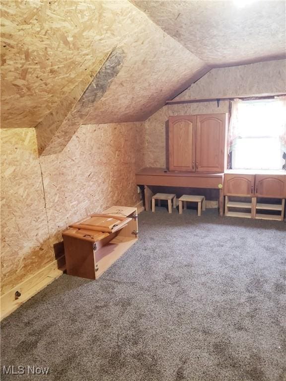 additional living space featuring vaulted ceiling and carpet flooring