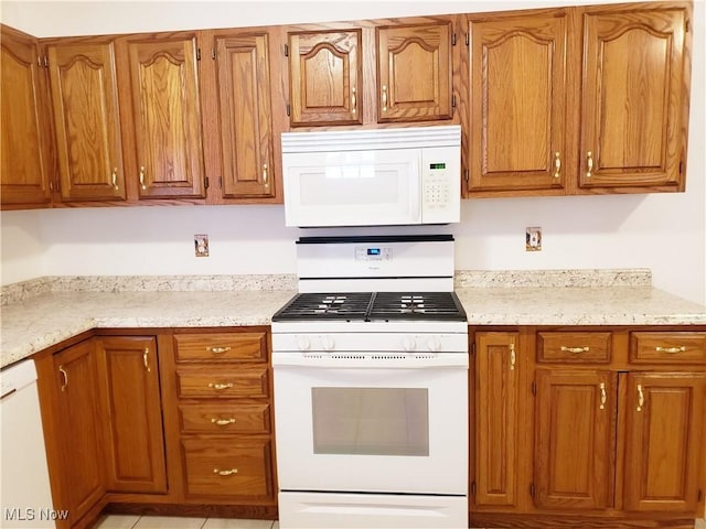 kitchen featuring light stone counters and white appliances