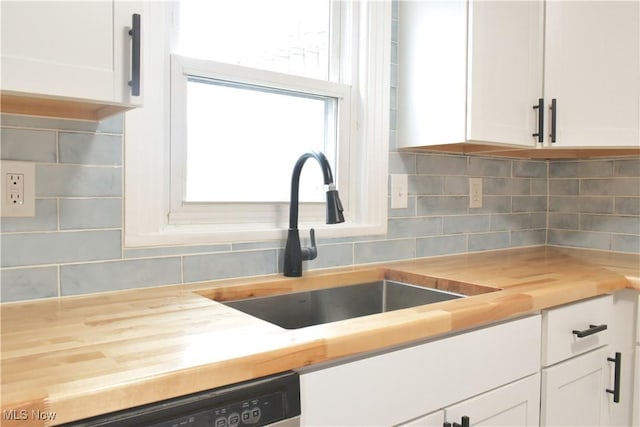 kitchen with white cabinetry, sink, backsplash, and wood counters