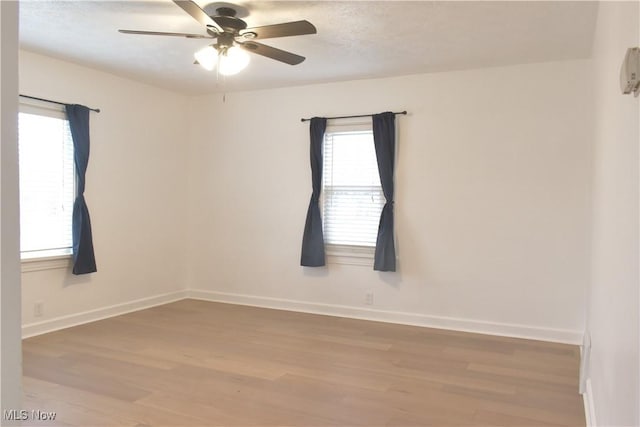 empty room with plenty of natural light, hardwood / wood-style floors, a textured ceiling, and ceiling fan