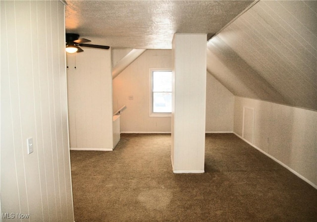 bonus room featuring ceiling fan, vaulted ceiling, a textured ceiling, and dark colored carpet