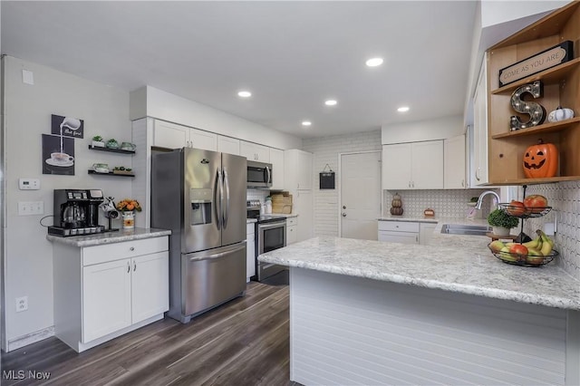 kitchen featuring sink, white cabinetry, appliances with stainless steel finishes, kitchen peninsula, and decorative backsplash