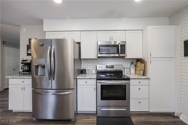 kitchen with appliances with stainless steel finishes, dark hardwood / wood-style floors, tasteful backsplash, white cabinets, and light stone counters