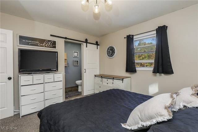 carpeted bedroom featuring a barn door and ensuite bath