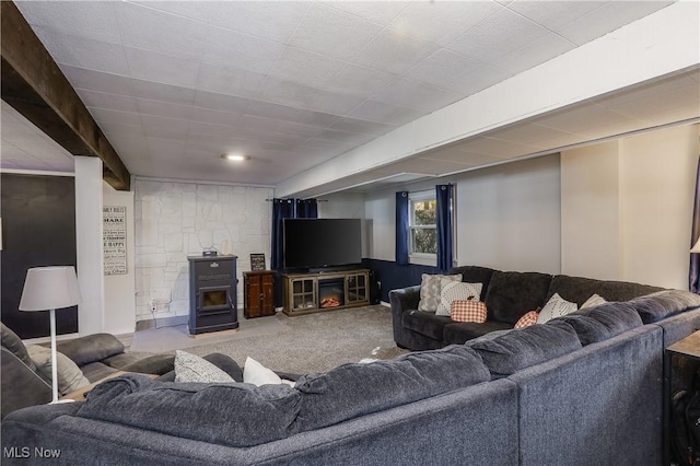 carpeted living room featuring beam ceiling and a wood stove