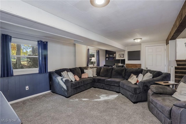 carpeted living room featuring wooden walls