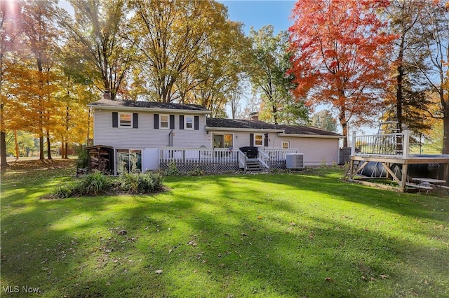 rear view of house with central AC unit, a deck, and a lawn