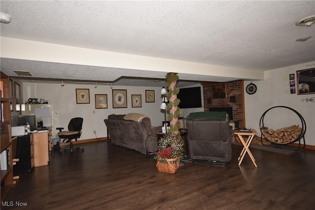 living room with a brick fireplace, dark wood-type flooring, and a textured ceiling