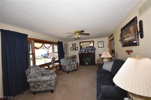 living room with ceiling fan, a textured ceiling, and carpet flooring