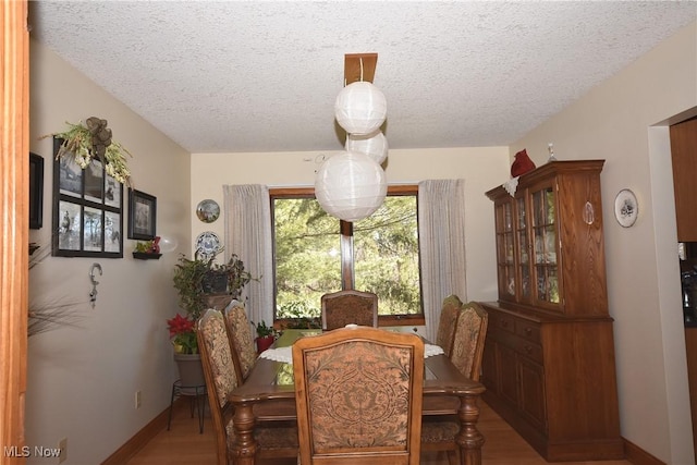 dining room with hardwood / wood-style floors and a textured ceiling