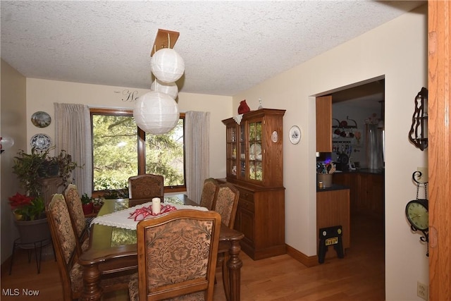 dining space with hardwood / wood-style floors and a textured ceiling