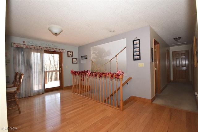 hall featuring a textured ceiling and light hardwood / wood-style flooring