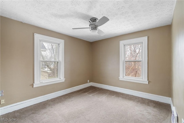 carpeted empty room featuring ceiling fan, a textured ceiling, and a wealth of natural light