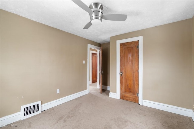 unfurnished bedroom with ceiling fan, light colored carpet, and a textured ceiling