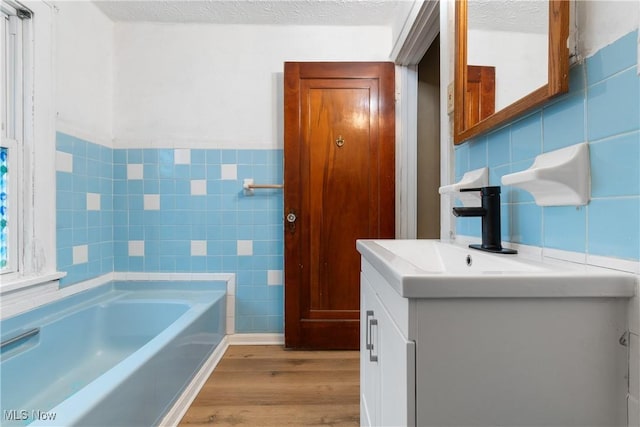 bathroom featuring hardwood / wood-style flooring, tile walls, and a textured ceiling