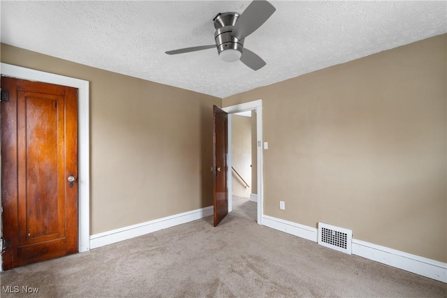 unfurnished bedroom with light carpet, ceiling fan, and a textured ceiling