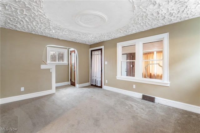 empty room with light carpet and a textured ceiling