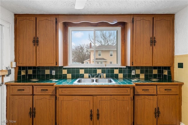 kitchen with sink, tile counters, and a textured ceiling