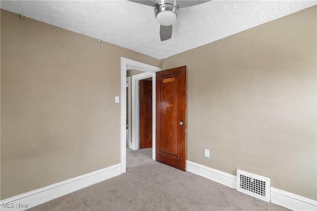 carpeted empty room featuring ceiling fan and a textured ceiling