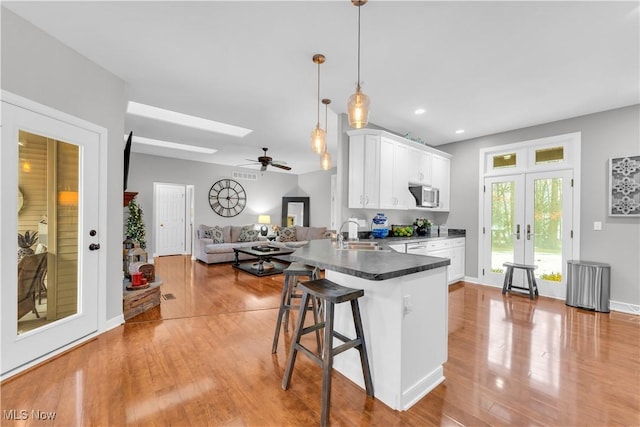 kitchen featuring a kitchen breakfast bar, white cabinets, french doors, decorative light fixtures, and kitchen peninsula