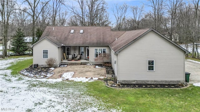 snow covered rear of property featuring a lawn