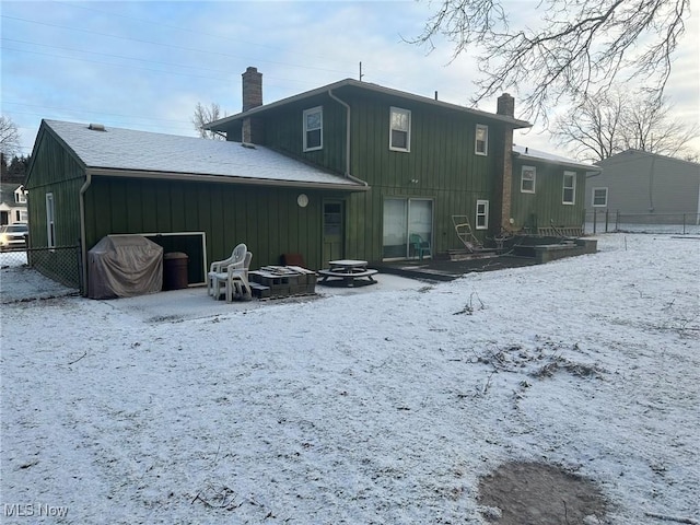 snow covered back of property featuring a fire pit