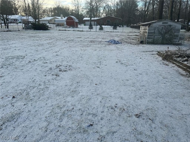 snowy yard featuring a shed