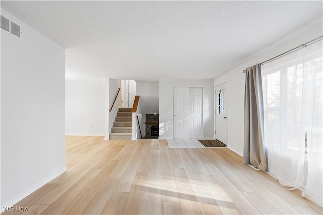 unfurnished living room featuring a textured ceiling and light wood-type flooring