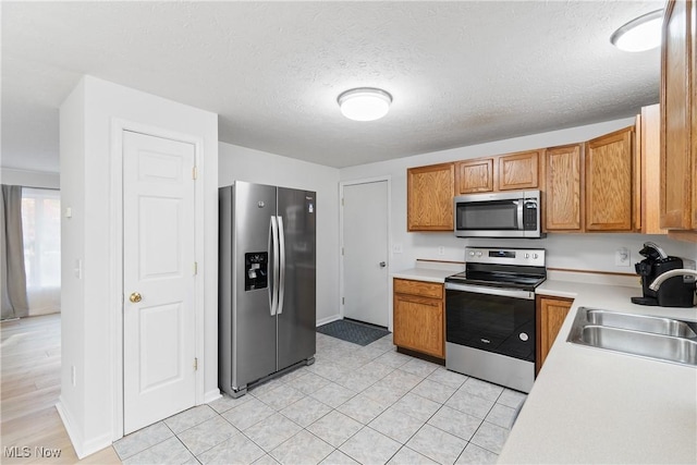 kitchen with stainless steel appliances, sink, and a textured ceiling