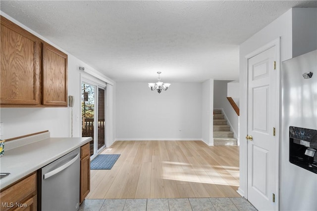 kitchen with stainless steel appliances, decorative light fixtures, light hardwood / wood-style floors, and a textured ceiling