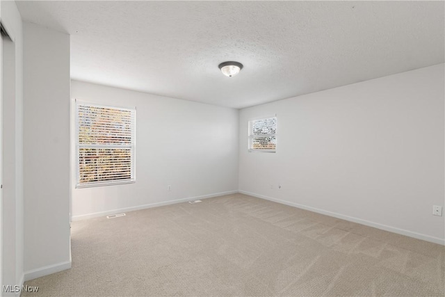 empty room with carpet and a textured ceiling